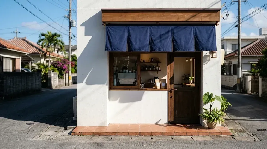 白いしっくいの壁に藍色ののれんが掛かった、小さなコーヒースタンドの店先(AI で生成したイメージ)